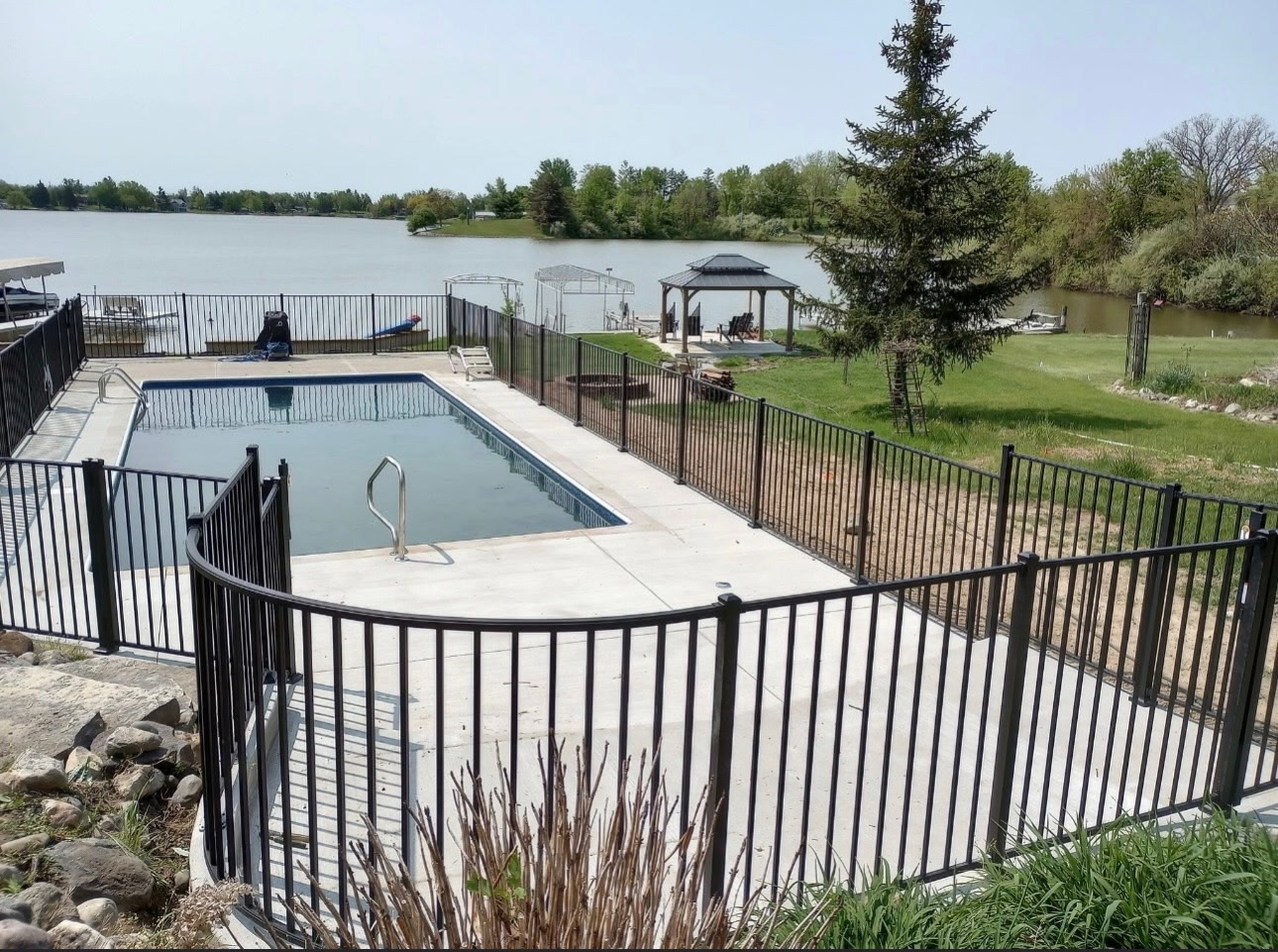 Black aluminum fence enclosing lakefront pool with Indiana lake view in background